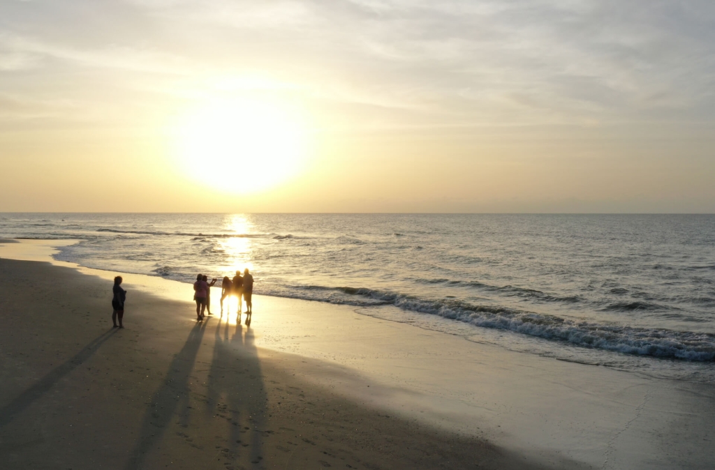 Group of people on beach watching the sunset