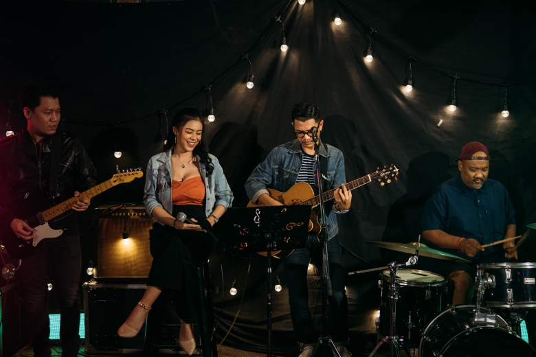 a band playing guitars, and drums and a girl with a microphone in her hand