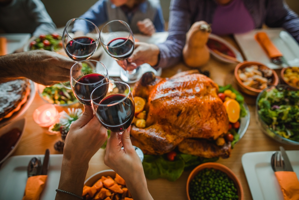 Family cheers red wine together over a Turkey and Thanksgiving feast