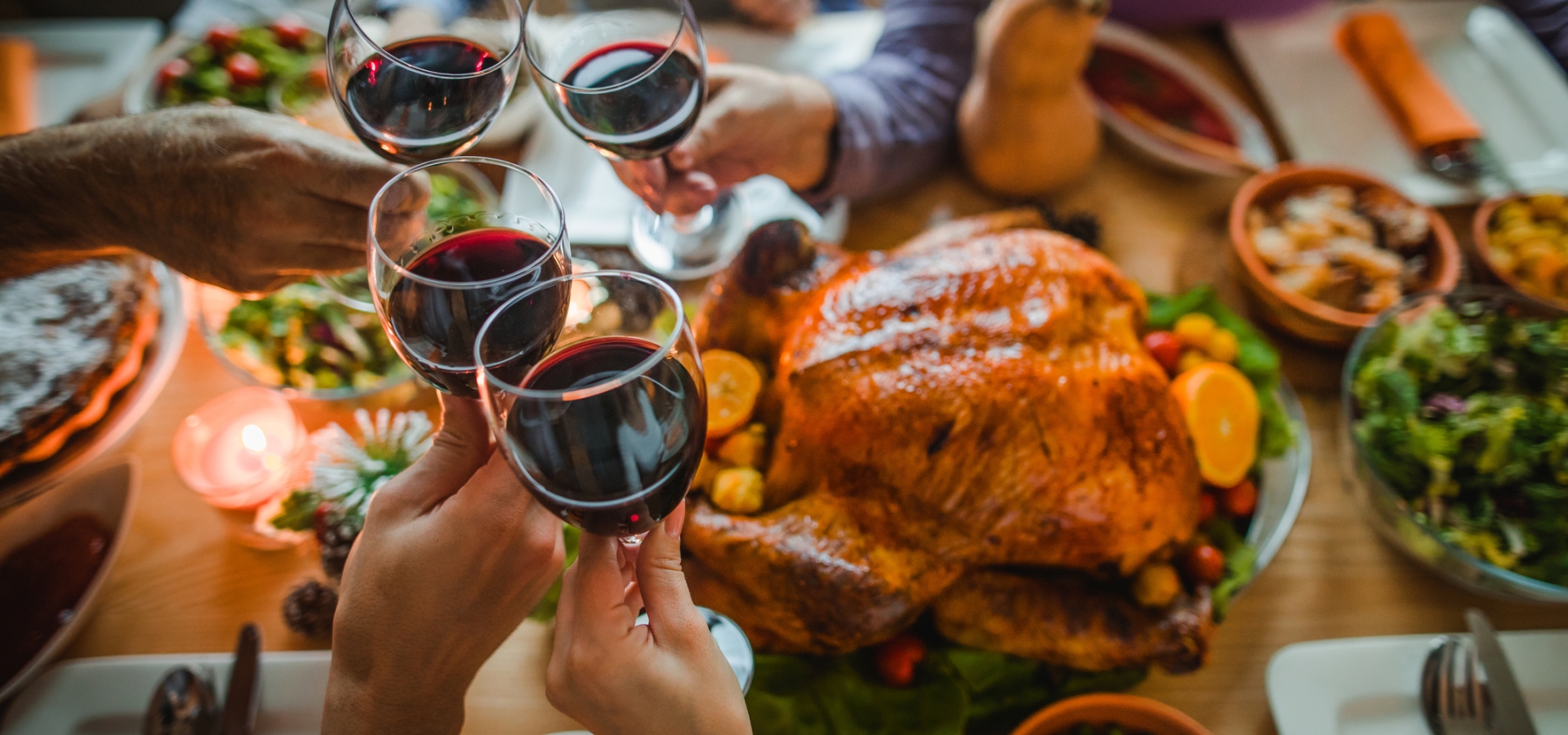 Family cheers red wine together over a Turkey and Thanksgiving feast