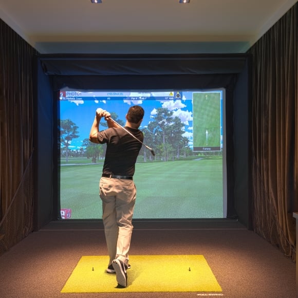 A guy using one of the golf simulators at 78Fitness