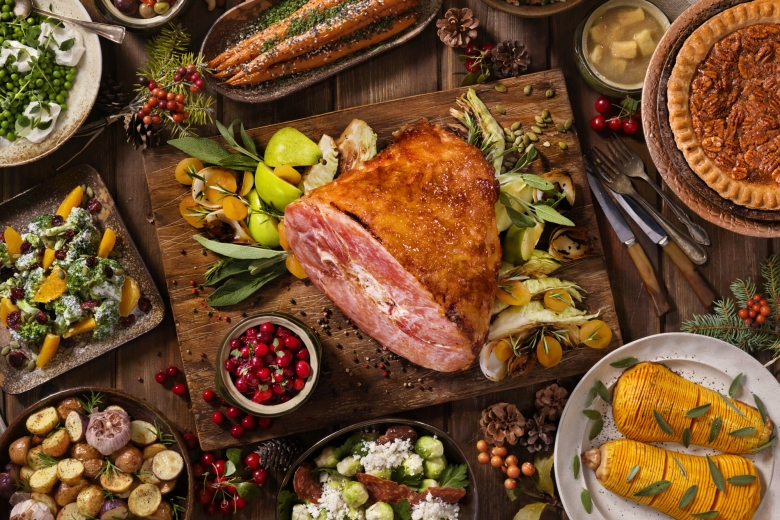 A holiday feast spread on the table featuring a glazed ham