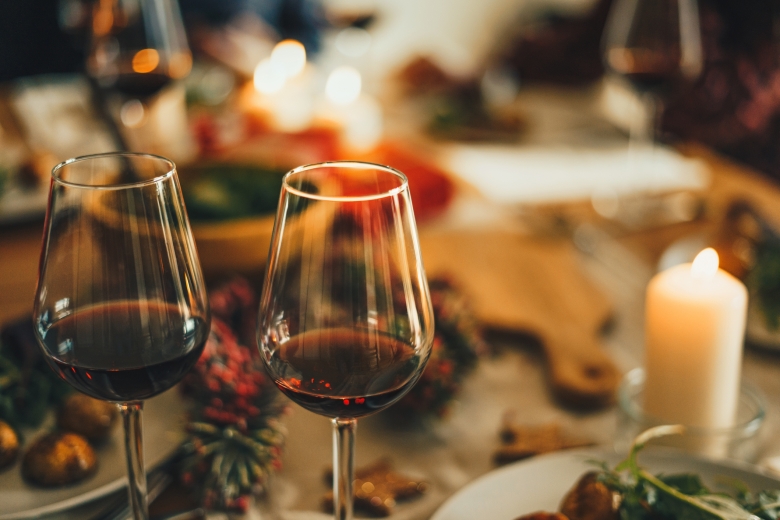 Two glasses of red wine overtop a blurred out Holiday meal spread