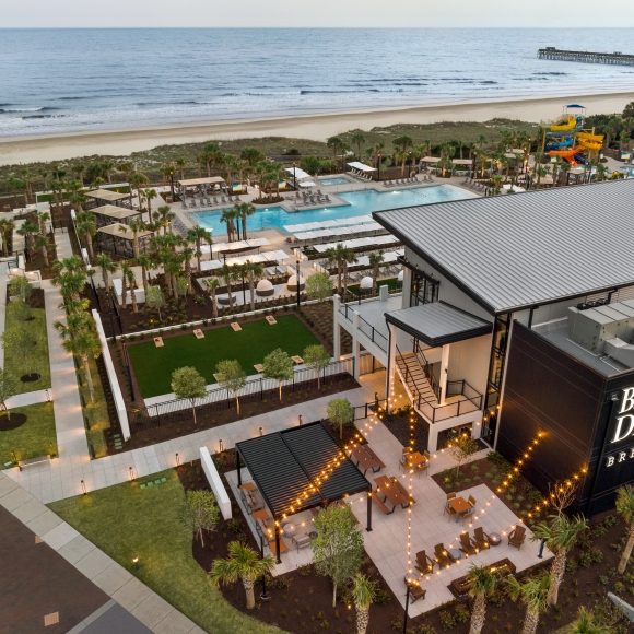 An aerial shot of a restaurant, pool, and beach in the background.