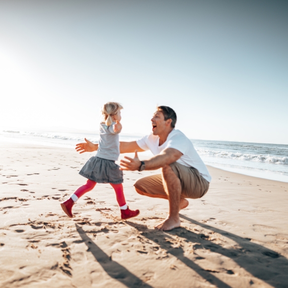 Daughter running into dads arms on the beach