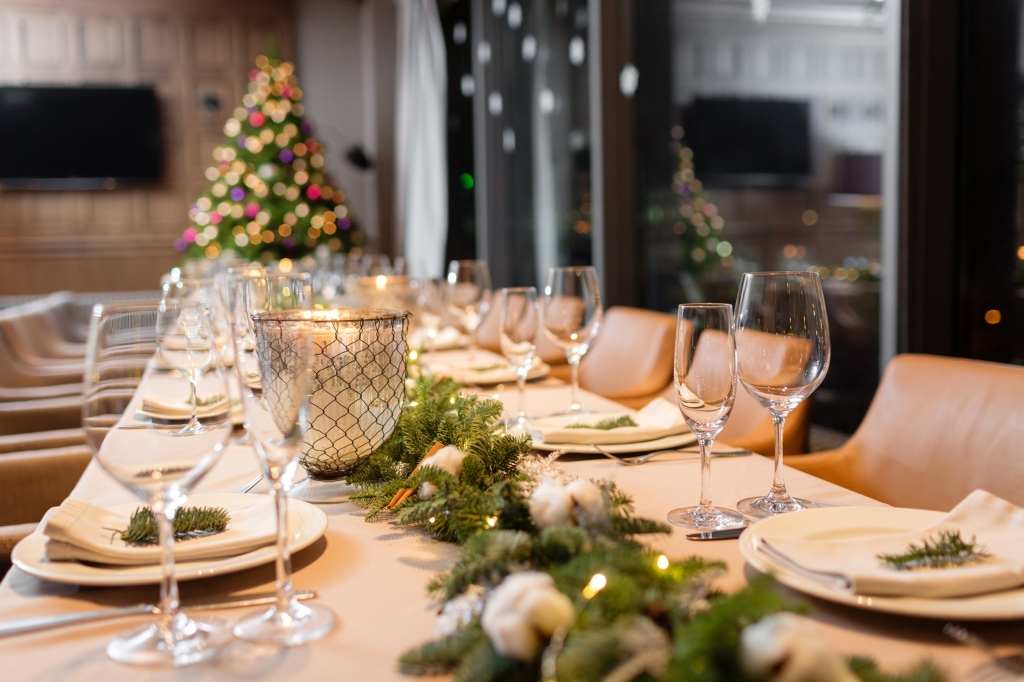 A long table set for a Christmas dinner with a Christmas tree in the background