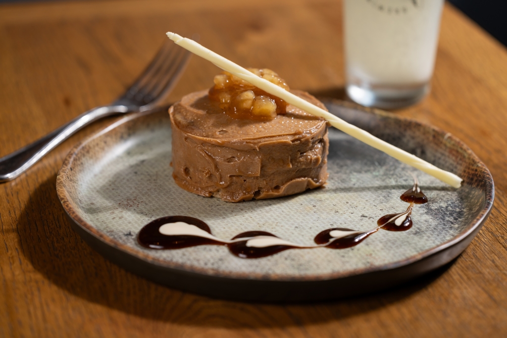 Personal Chocolate cake with cooked cinnamon apples on top. Plated with a white chocolate stick and chocolate drizzle on the plate